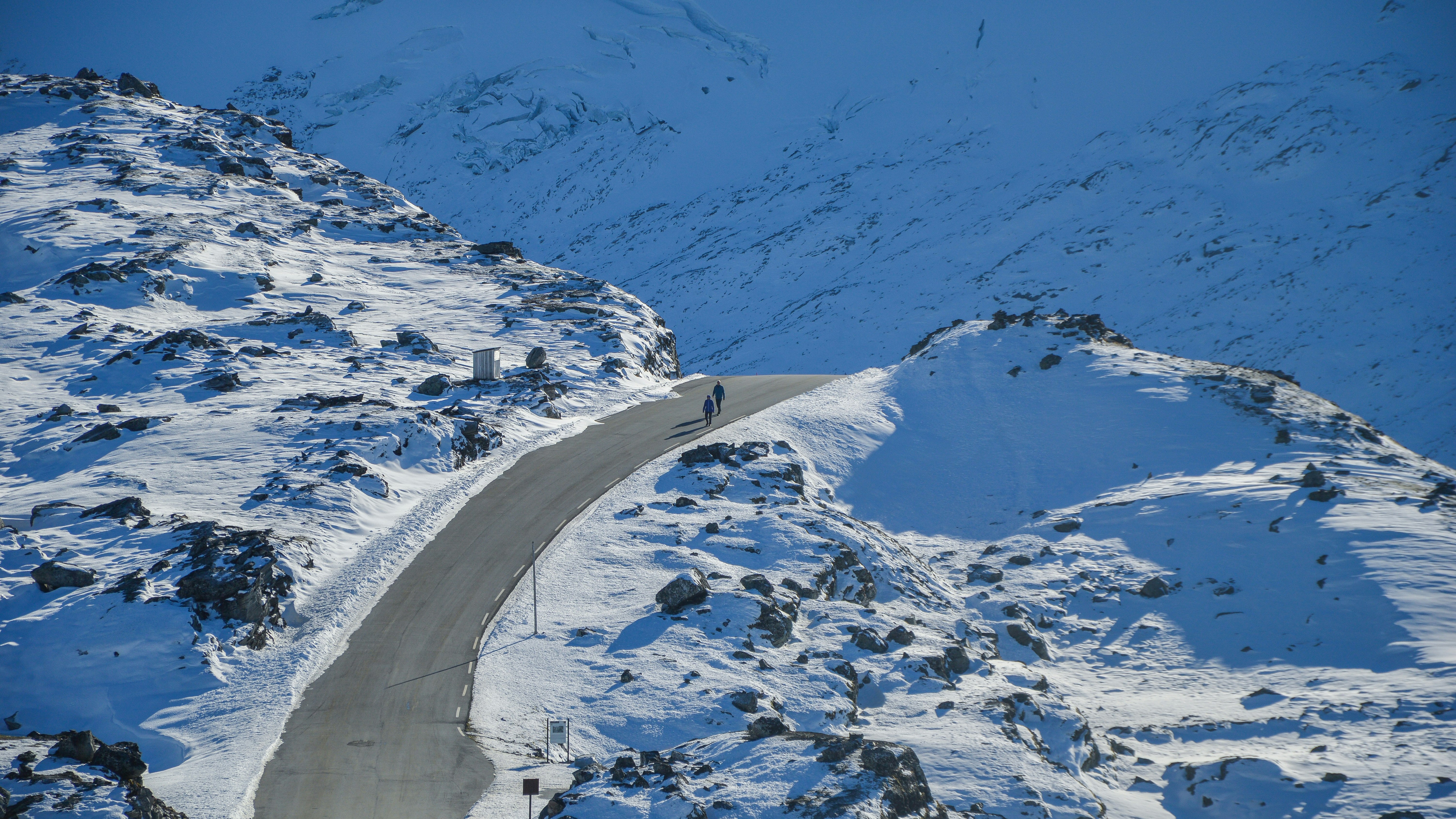 bird's eye photography of two people walking on road between snowfield